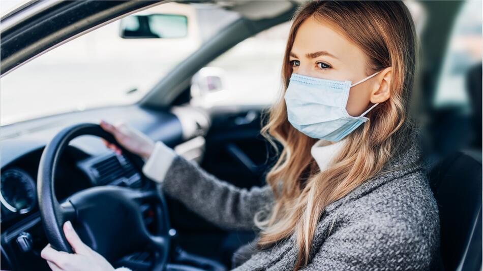 Frau mit Maske im Auto